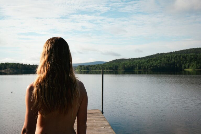 A woman sitting on a dock looking at the water